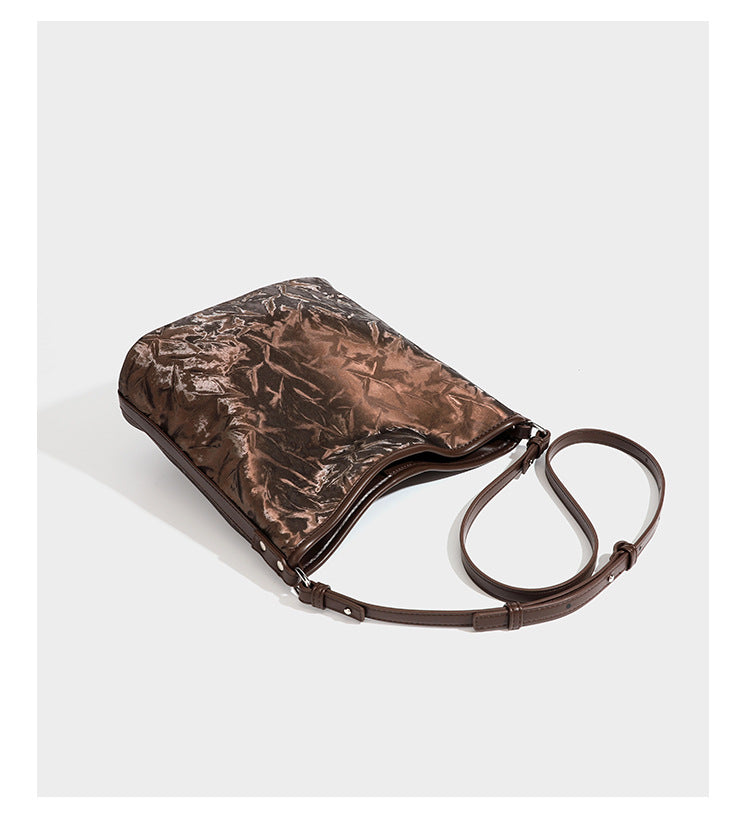Große Hobo-Schultertasche mit Knitterglanz in Dunkelbraun, schmalem verstellbarem Riemen, geknoteten Metalldetails und seitlich angesetzter Klappe