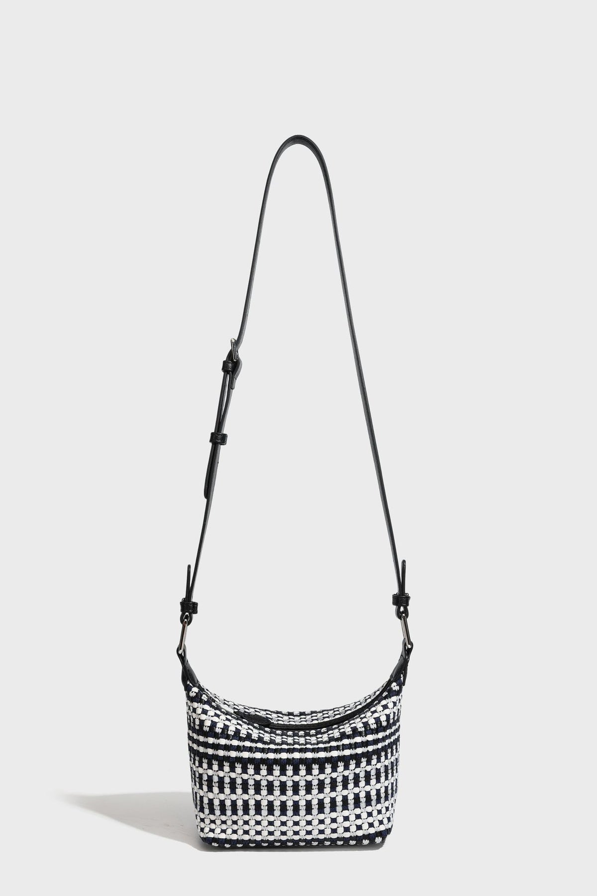Small crescent shoulder bag in black-and-white woven textile with smooth black leather-look trim, zip-top closure, knotted