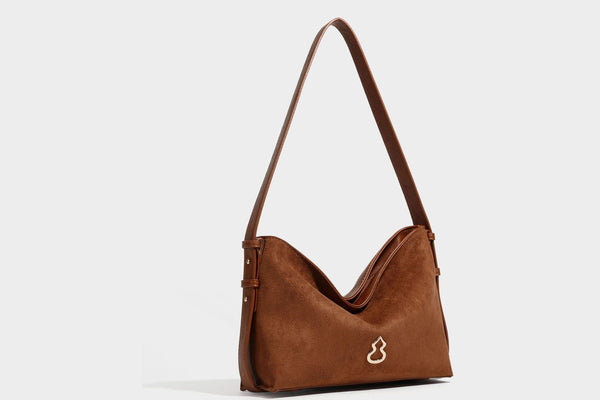 Slouchy suede-finish brown shoulder bag with long single strap and small gold-tone logo emblem on front, detail view 24