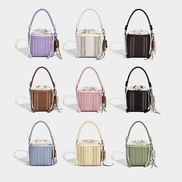 Small woven bucket bag with drawstring top, braided handle, detachable crossbody strap, and silver-tone ring hardware, detail