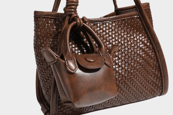 Strukturierte Tote-Bag mit Webstruktur in Braun, glattem, lederähnlichem Besatz, geknoteten Tragegriffen und einer befestigten Mini-Beuteltasche mit Kordelzug