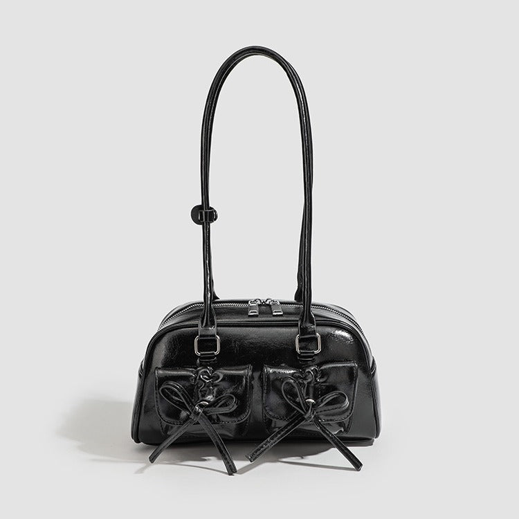 Compact glossy leather-look shoulder bag with bow-drawstring front pockets, zip-top closure, dual top handles, and, front