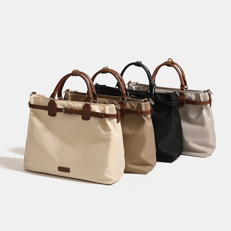 Structured matte tote bag with leather-look brown trim, dual top handles, zip closure, and detachable shoulder strap, detail