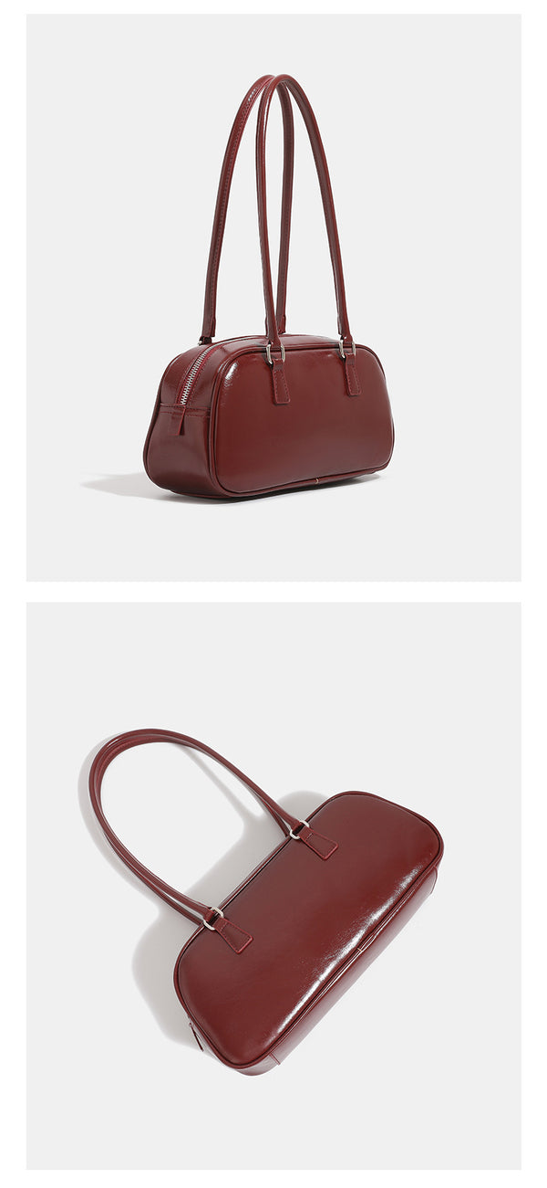 Rounded baguette shoulder bag with glossy leather-look finish, double-pull zip top, dual top handles, and silver-tone, detail