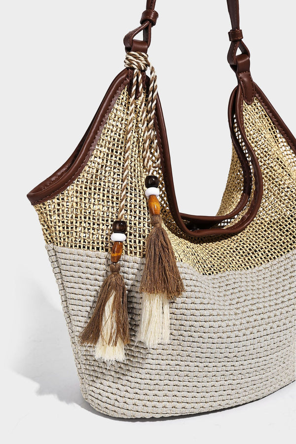Two-tone beige and cream woven straw hobo shoulder bag with brown leather-look trim, long shoulder strap, and tassel-bead