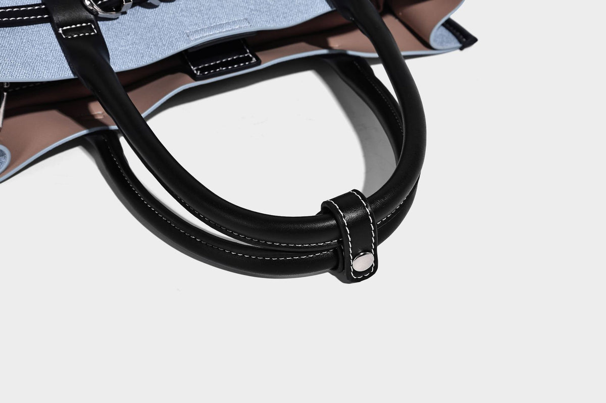 Structured rectangular tote satchel in denim-look fabric with dark trim, knotted front strap hardware, and detachable, detail
