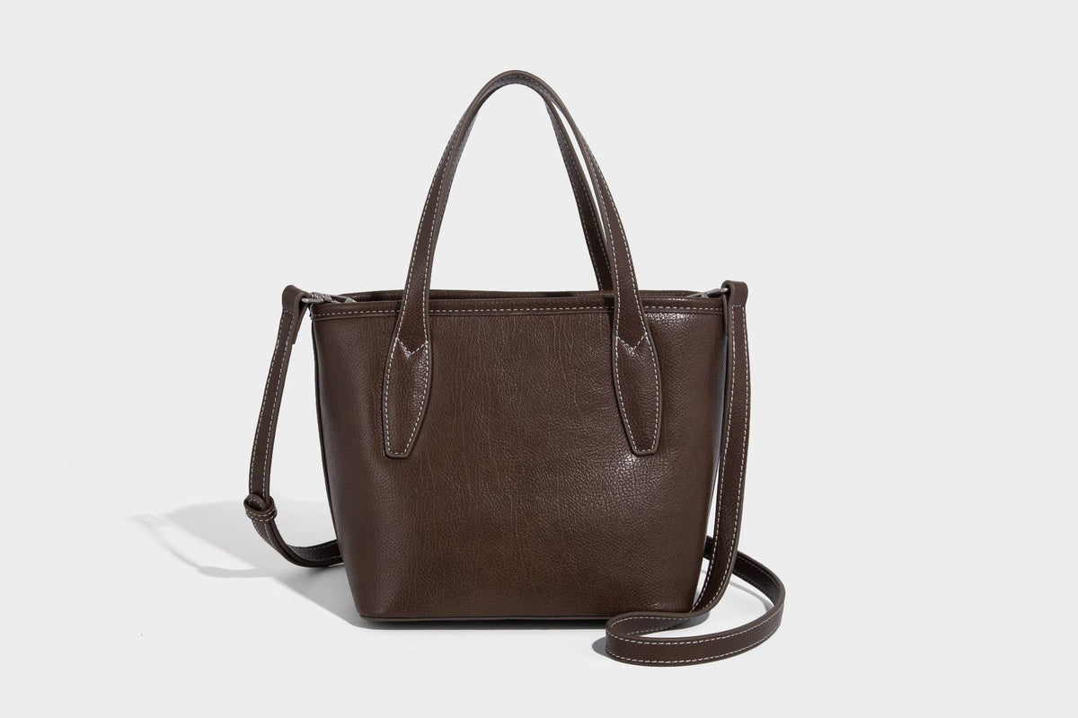 Compact structured bucket tote bag with pebbled textured finish, dual top handles, silver-tone lock hardware, and detachable
