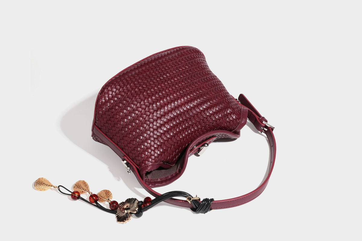 Small woven-look leather-look flap shoulder hobo bag in burgundy with silver-tone hardware and decorative tassel charm