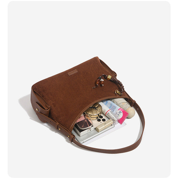 Caramel brown slouchy hobo shoulder bag with matte suede-like finish, braided tassel charm, brass-tone hardware, and, detail