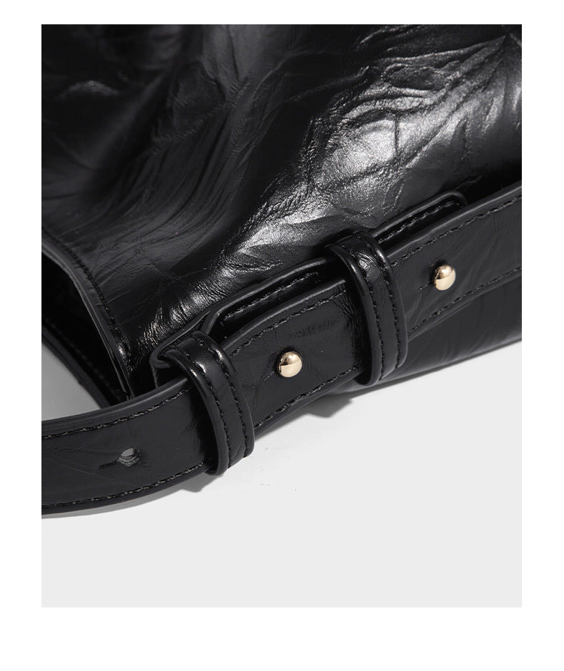 Large slouchy hobo shoulder bag in glossy crinkle leather-look finish with gold-tone emblem hardware and adjustable strap