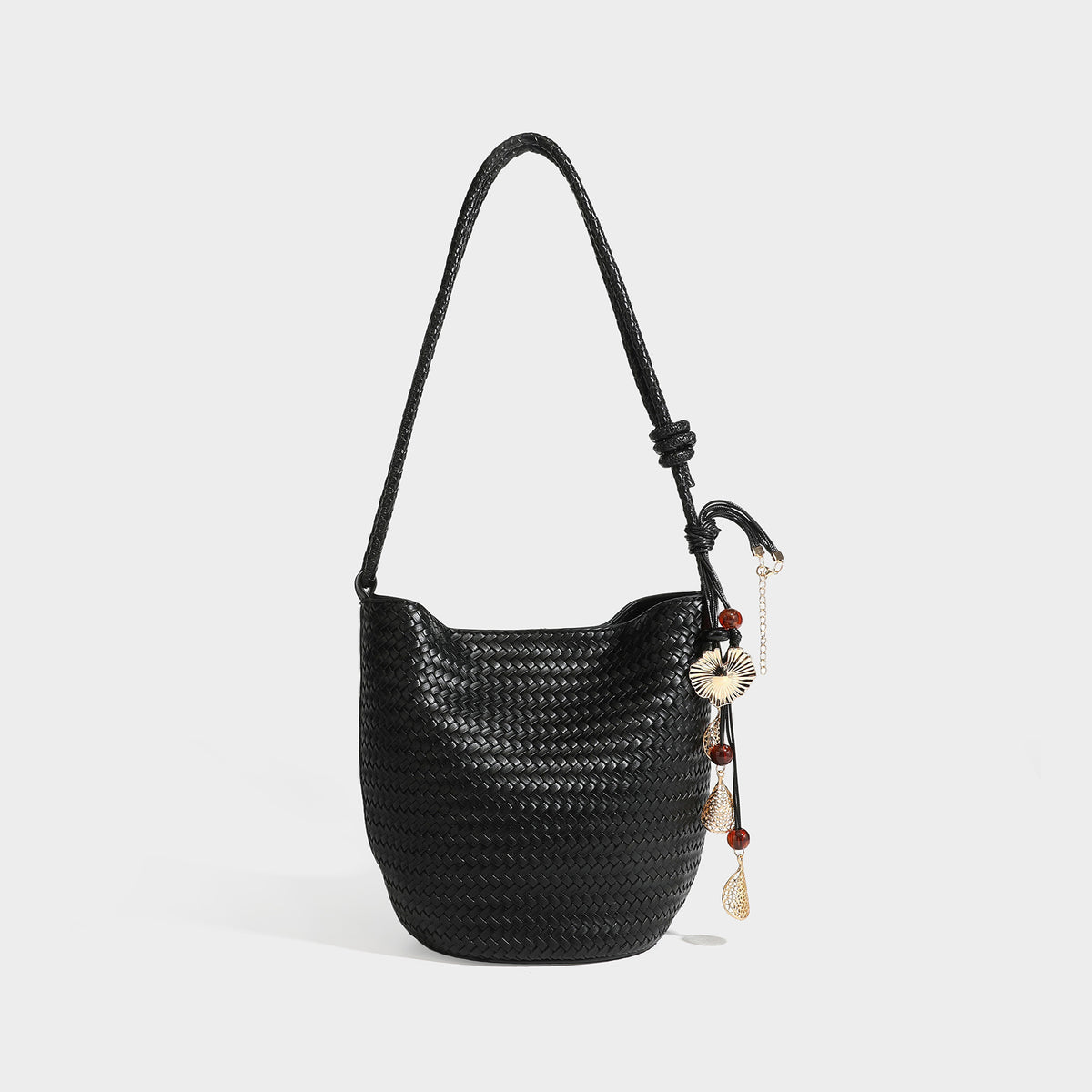 Olive green woven leather-look bucket bag with braided crossbody strap, knotted adjustment, and gold-tone tassel charm with