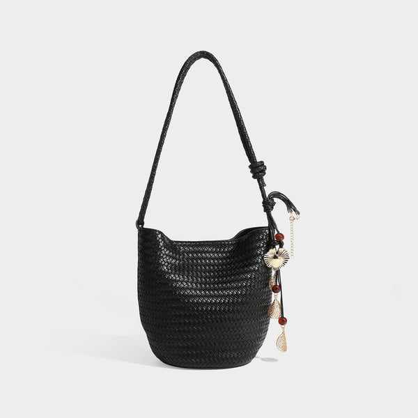 Olive green woven leather-look bucket bag with braided crossbody strap, knotted adjustment, and gold-tone tassel charm with