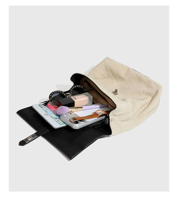 Strukturierter beigefarbener Rucksack aus gewebtem Canvas mit schwarzer Klappe in Lederoptik, Drehverschluss, Tragegriff und flachem Schulter