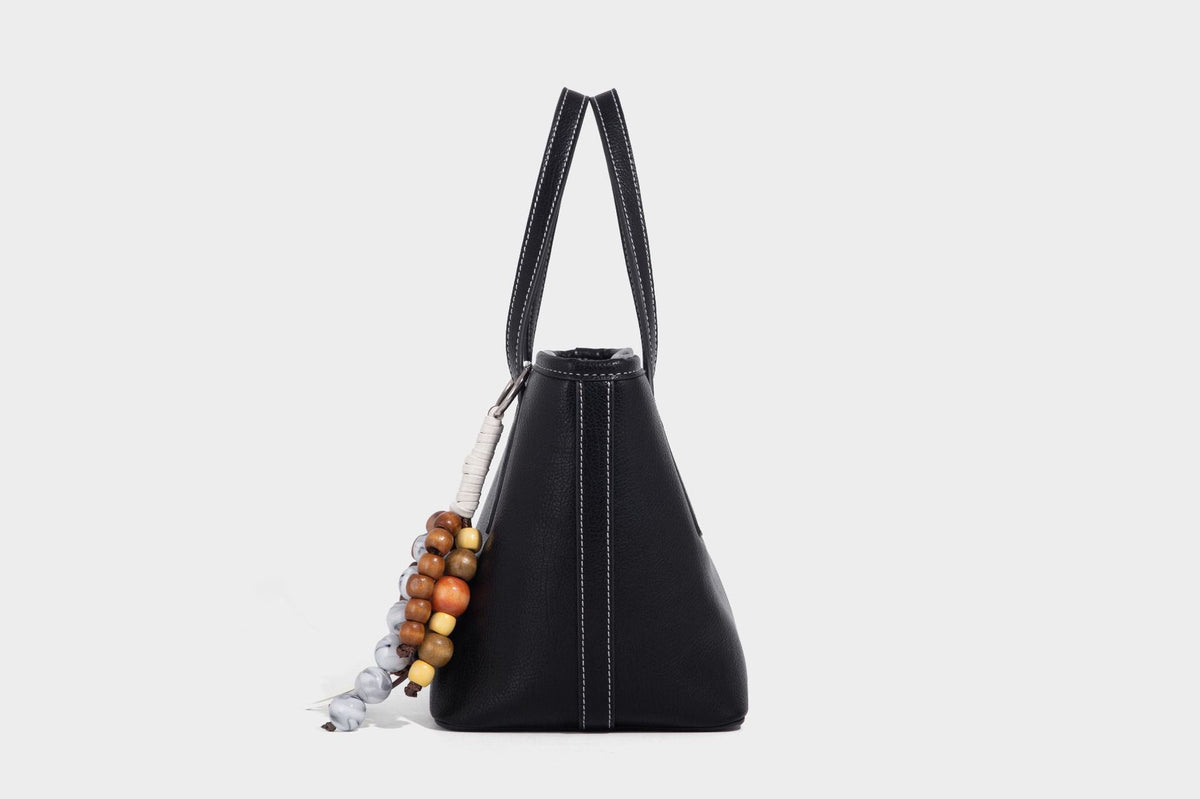 Compact structured bucket tote bag with pebbled textured finish, dual top handles, silver-tone lock hardware, and detachable