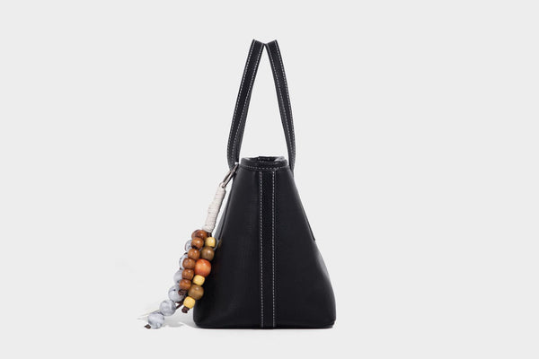 Compact structured bucket tote bag with pebbled textured finish, dual top handles, silver-tone lock hardware, and detachable
