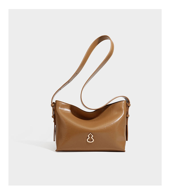 Lässige Hobo-Schultertasche mit offenem oberen Abschluss in glänzender karamellfarbener Lederoptik mit goldfarbenen Logo-Beschlägen und langem, verstellbarem