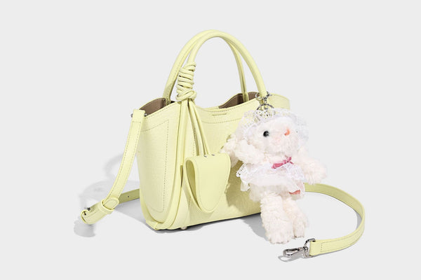 Structured mini tote bag in pebbled leather-look finish with knotted top handles, front flap pocket, and detachable shoulder