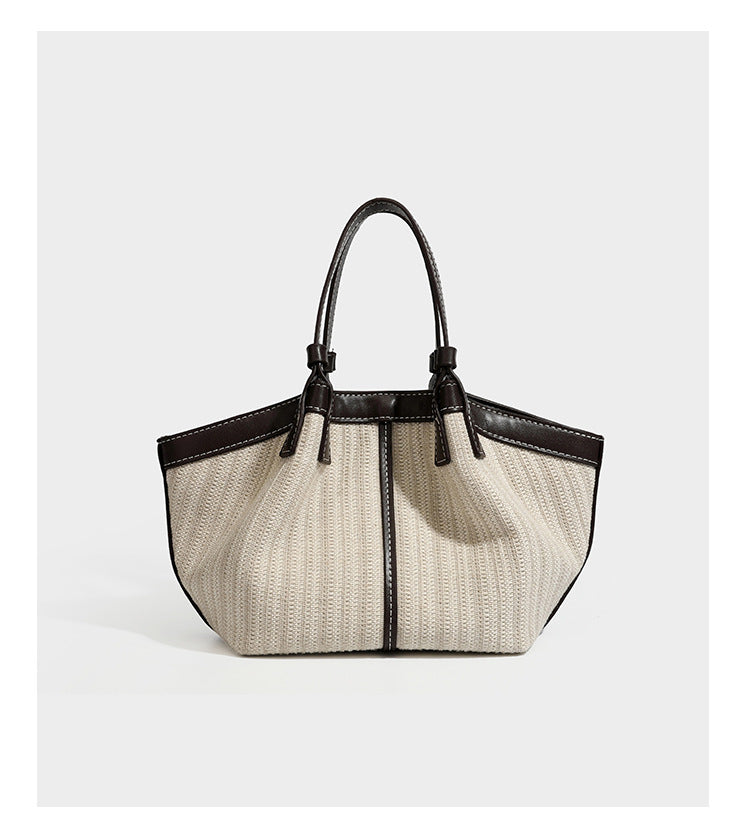 Cremefarbene geflochtene Tote-Bag mit dunkelbraunen Besätzen in Lederoptik, kontrastierenden weißen Nähten, zwei oberen Henkeln und abnehmbarem Schulter