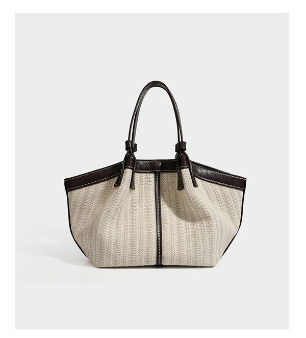 Cremefarbene geflochtene Tote-Bag mit dunkelbraunen Besätzen in Lederoptik, kontrastierenden weißen Nähten, zwei oberen Henkeln und abnehmbarem Schulter