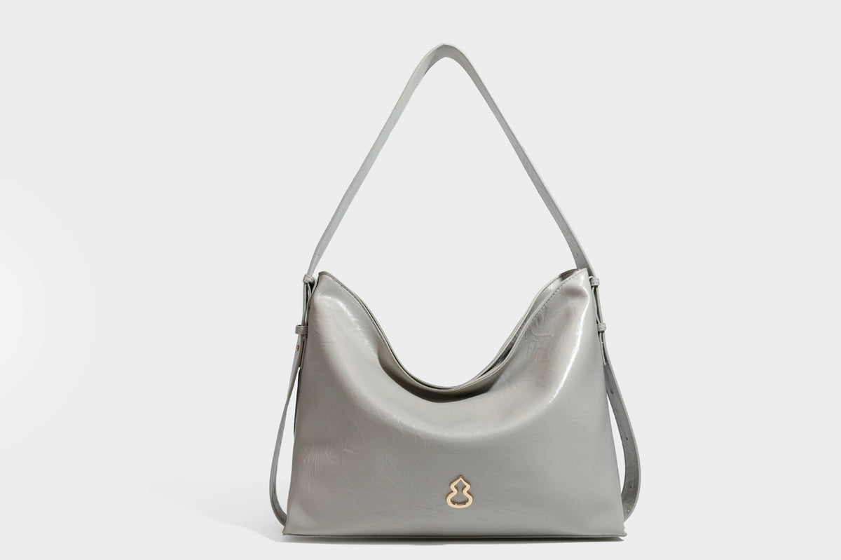 Lässig fallende Hobo-Schultertasche mit offenem Oberteil aus glänzender, karamellbrauner Lederoptik, mit Logo-Beschlägen in Goldoptik und langem, verstellbarem