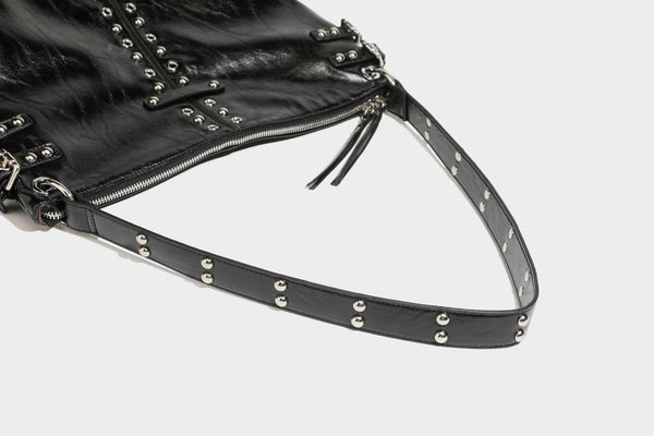 Black glossy leather-look slouchy shoulder bag with silver stud and eyelet hardware, top zip closure, front zip pocket, and