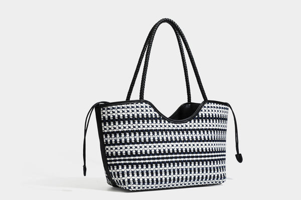 Large woven checker-pattern tote bag with dark braided shoulder straps, leather-look trim, and drawstring side ties, detail