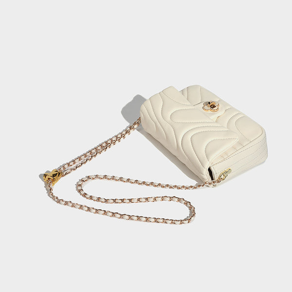 Compact cream quilted flap crossbody bag with wave stitching, gold-tone chain strap, and four-petal turn-lock clasp, detail