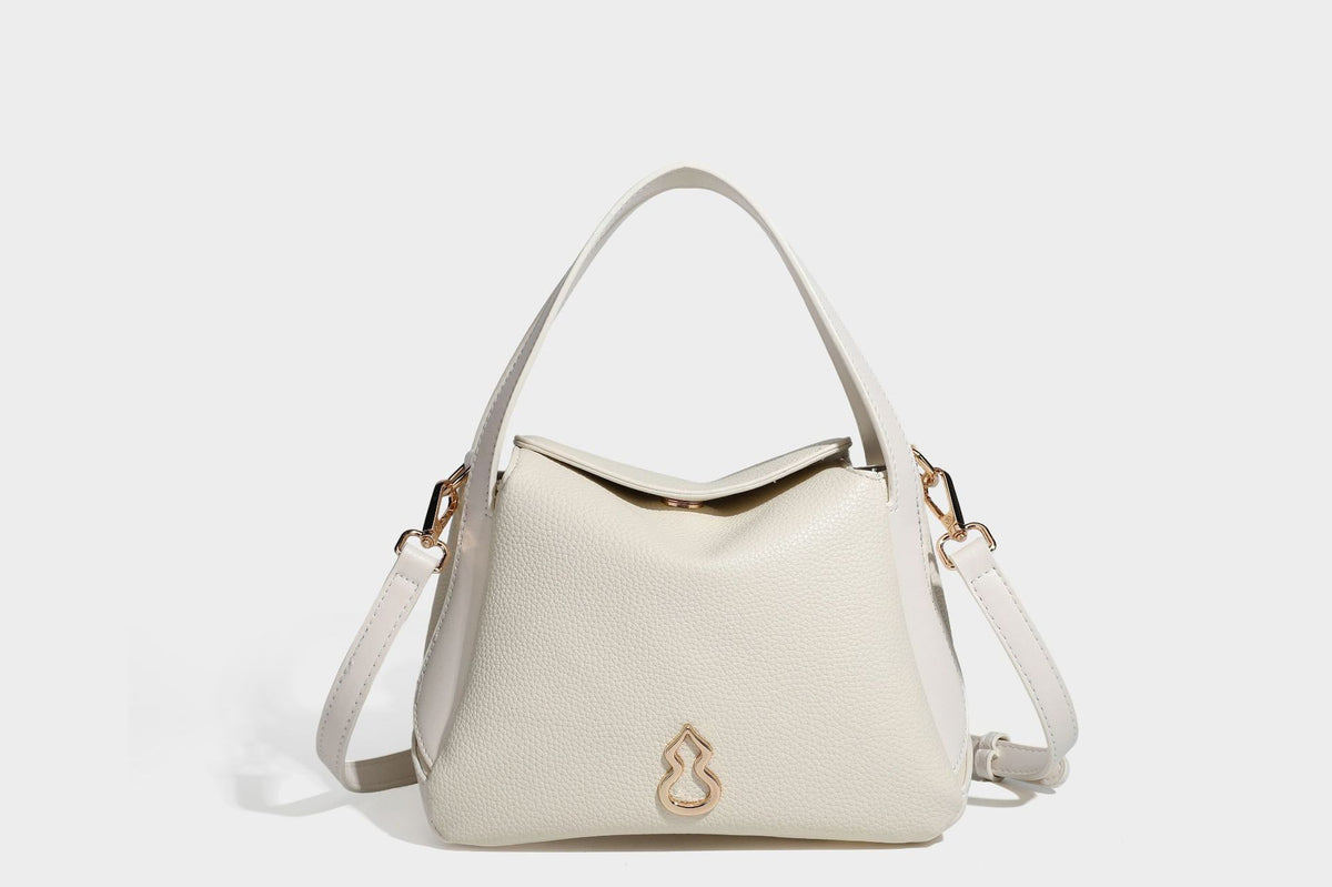 Structured pebbled leather-look shoulder bag with flap top, gold-tone emblem hardware, dual top handles, and detachable