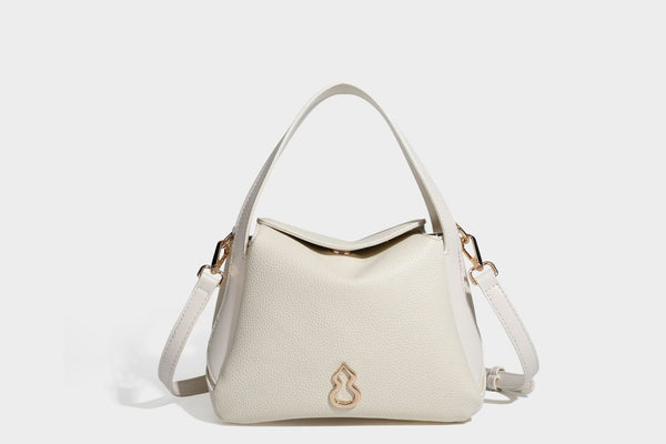 Structured pebbled leather-look shoulder bag with flap top, gold-tone emblem hardware, dual top handles, and detachable