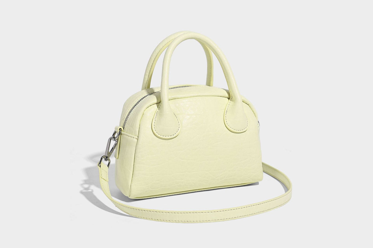 Mini-Tasche mit strukturierter Kuppelform und Tragegriff, in Pastellgelb mit genarbter Lederoptik, silberfarbenen Metallbeschlägen und abnehmbarem