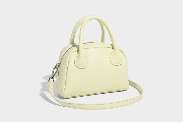 Mini-Tasche mit strukturierter Kuppelform und Tragegriff, in Pastellgelb mit genarbter Lederoptik, silberfarbenen Metallbeschlägen und abnehmbarem