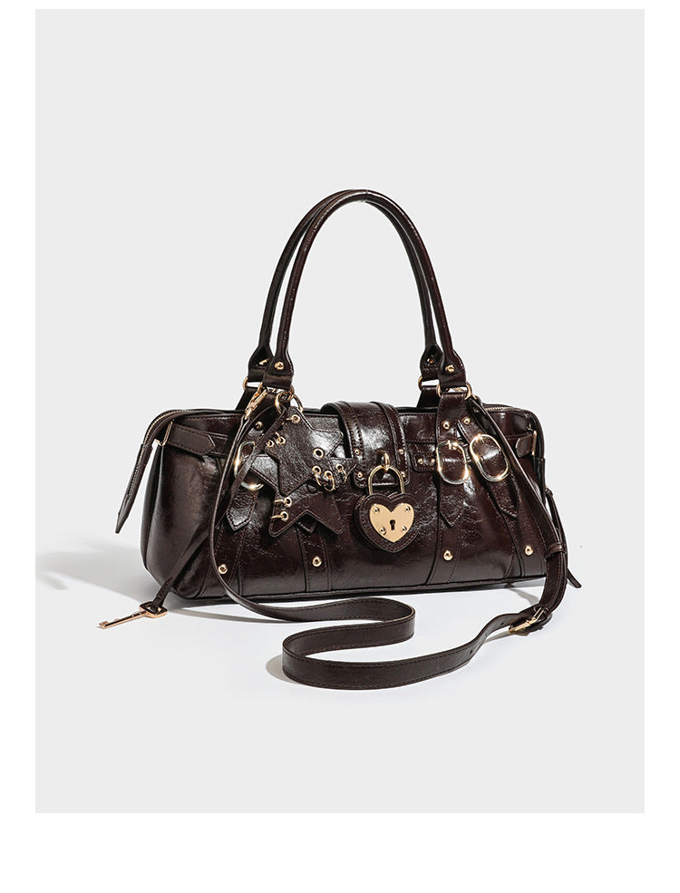 Dark brown glossy crinkled leather-look barrel bag with gold heart lock, dome studs, star charm, dual top handles and, detail