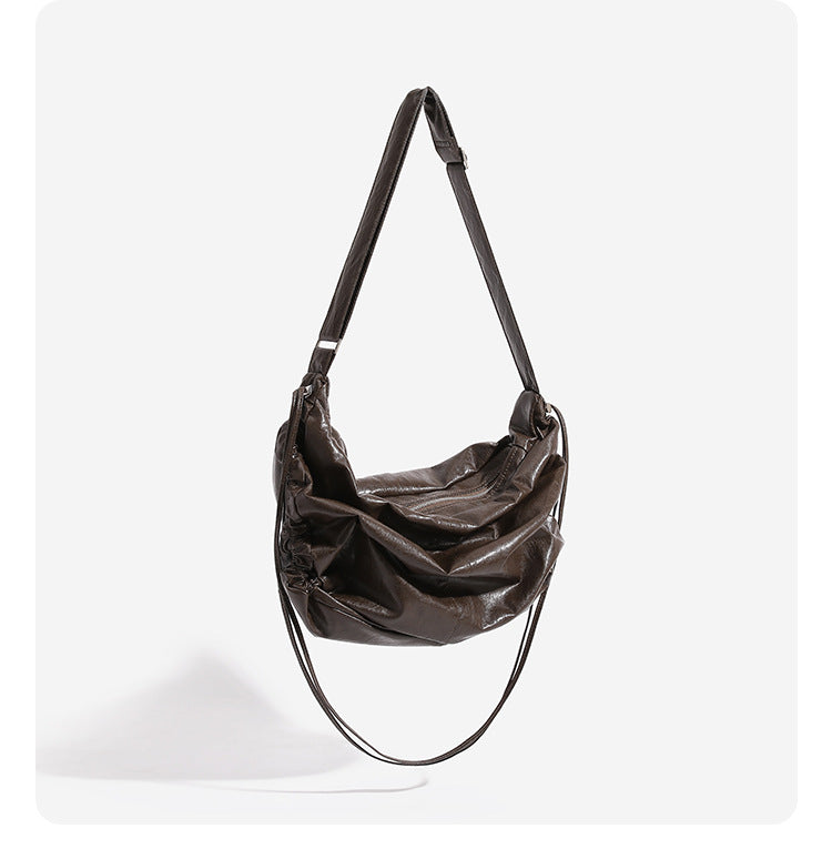 Oversized slouchy hobo shoulder bag with glossy crinkled leather-look finish, drawstring gathered sides, and silver-tone