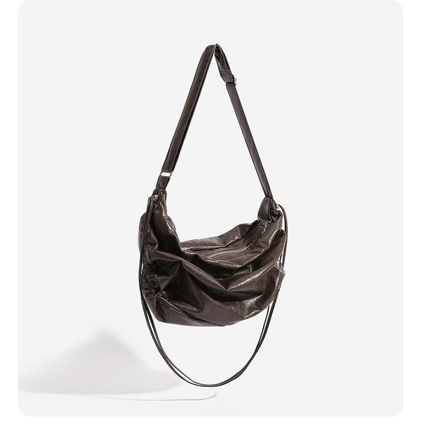 Oversized slouchy hobo shoulder bag with glossy crinkled leather-look finish, drawstring gathered sides, and silver-tone