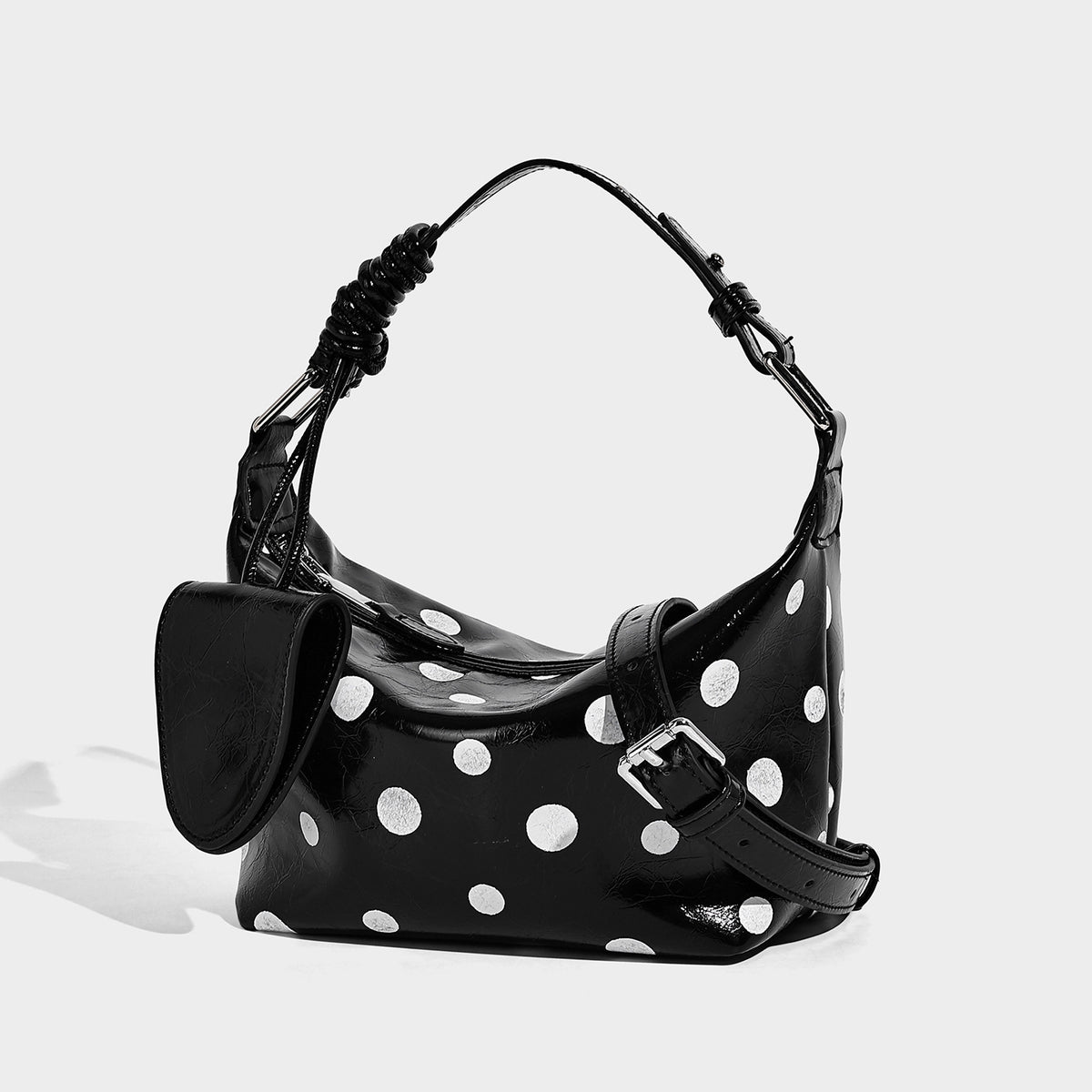 Compact black polka-dot glossy hobo shoulder bag with white dots, zip closure, gunmetal hardware, and attached front flap