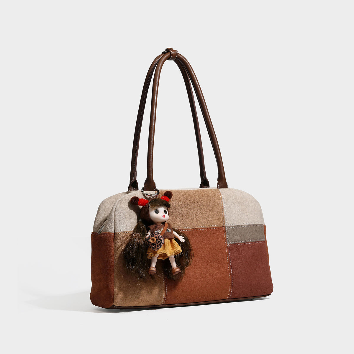 Kastige Schultertasche im Patchwork-Design in Velourslederoptik mit beigefarbenen, beigen, rostbraunen und braunen Partien, zwei braunen Riemen und hängendem Puppenanhänger