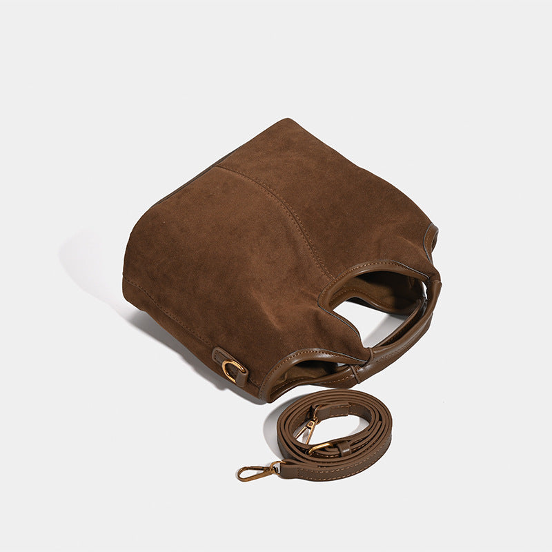 Wandelbarer Shopper in mattem Schokoladenbraun mit Velourslederoptik, abgerundeten Henkeln und abnehmbarem Schulterriemen, goldfarbene Details