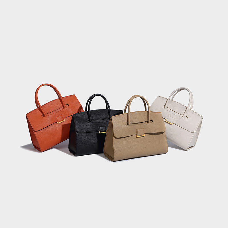 Structured trapezoidal top-handle satchel with pebbled matte finish, flap front, and square gold-tone turn-lock clasp, detail