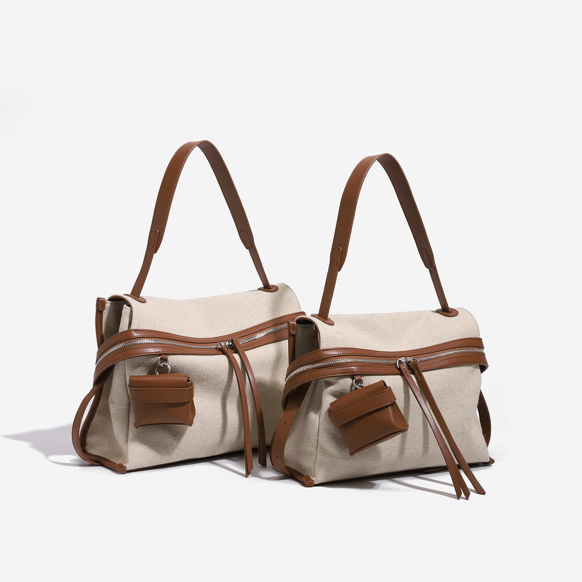 Messenger-Schultertasche aus cremefarbenem Canvas mit Besätzen in hellbrauner Lederoptik, zwei Reißverschlüssen, Quastenanhängern und aufgesetztem Mini-Fronttäschchen