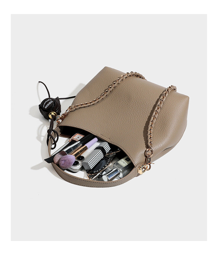 Schultertasche in genarbter Lederoptik im Hobo-Stil mit goldfarbener Kette, kurzem Tragegriff und dekorativem Anhänger an der Seite, Detailansicht
