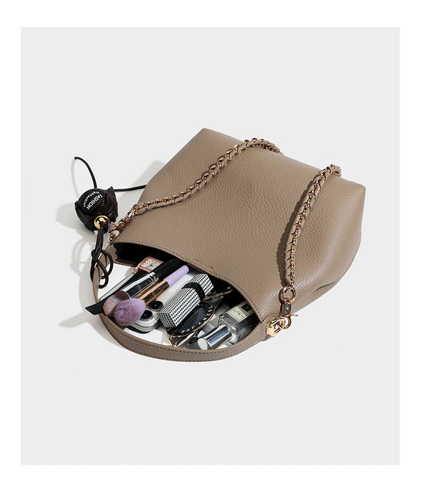 Schultertasche in genarbter Lederoptik im Hobo-Stil mit goldfarbener Kette, kurzem Tragegriff und dekorativem Anhänger an der Seite, Detailansicht