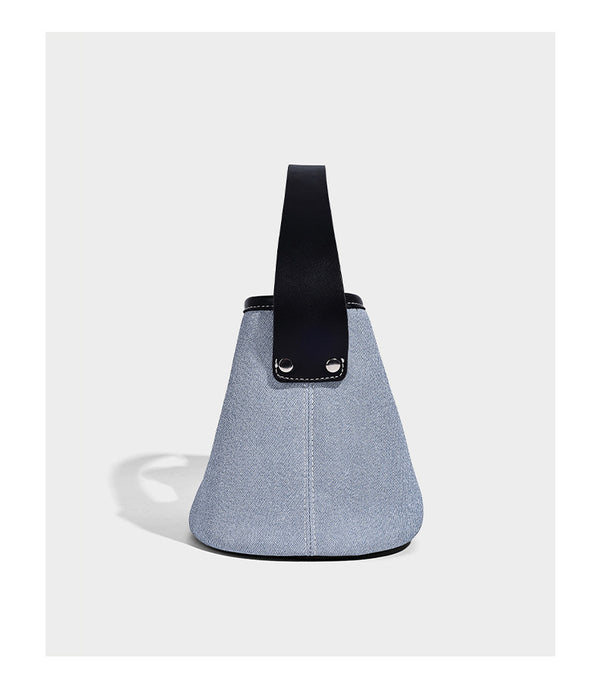 Small denim-look bucket bag with black leather-look trim, pink tulip flower charm, and adjustable crossbody strap, detail