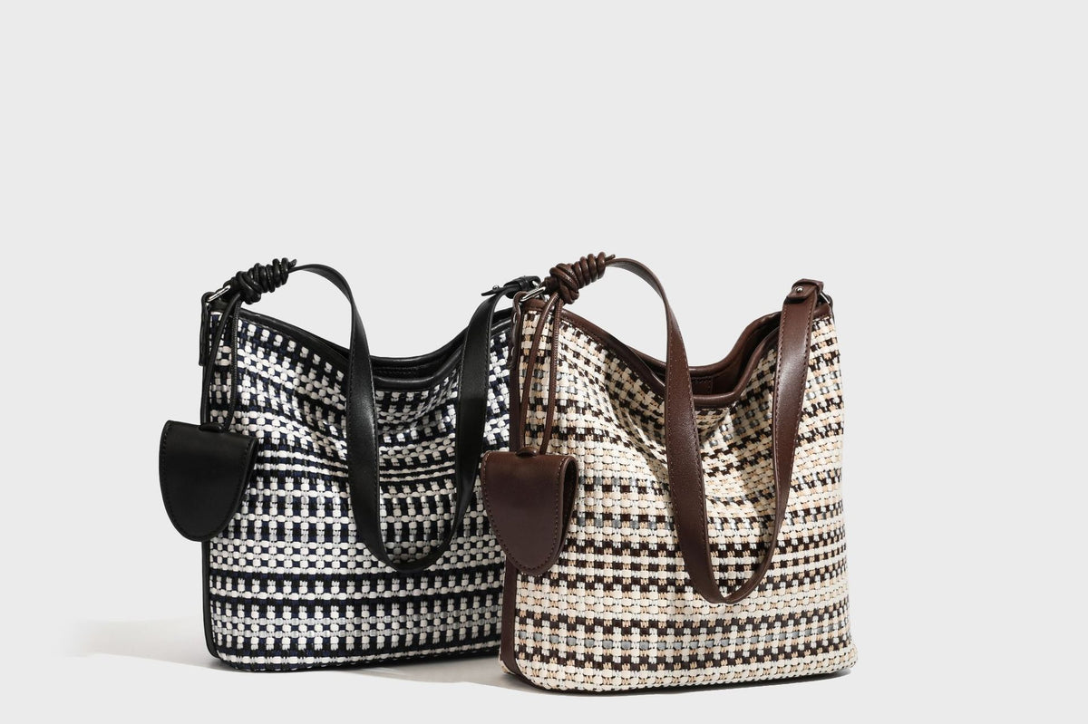 Woven stripe bucket shoulder bag in cream and dark brown with leather-look trim, knotted adjustable strap, and small shield