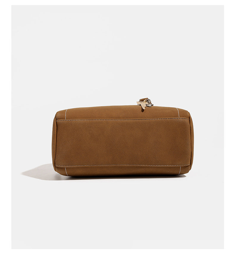 Kompakte, strukturierte Henkeltasche mit matter genarbter Oberfläche, geknoteten Doppelhenkeln, goldenem Schlüsselanhänger und abnehmbarem, Detail