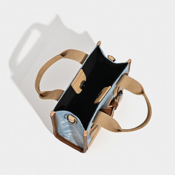 Structured mini tote bag in washed denim and neutral colorblock with brown leather-look trim and front belt buckle detail