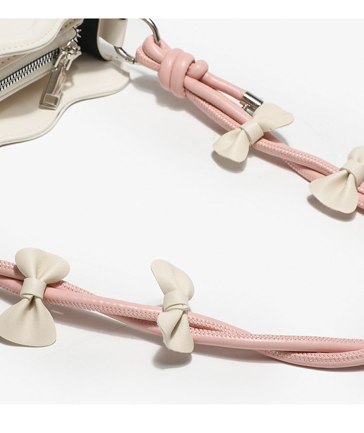 Small structured scalloped-edge shoulder bag with bow-tied pink cord strap and silver heart charm pendant, detail view 14