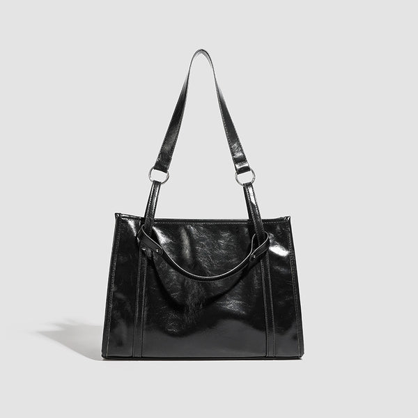 Large structured glossy leather-look tote bag with dual top handles and long shoulder strap in burnished brown, detail view 7