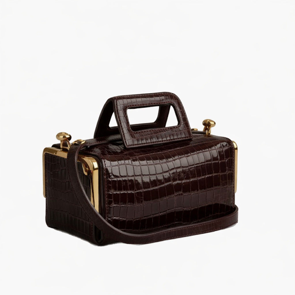 Compact dark brown leather-look top-handle bag with gold-tone ball-tip frame hardware and detachable adjustable crossbody
