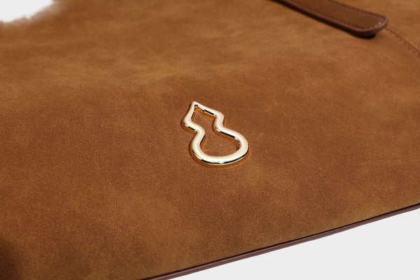 Oversized suede-finish tote shoulder bag in caramel brown with slim leather-look straps and gold-tone logo hardware, detail