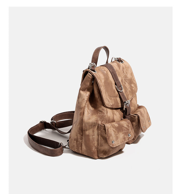 Compact distressed leather-look tan-brown backpack handbag with flap-and-buckle closure, two front patch pockets, top handle